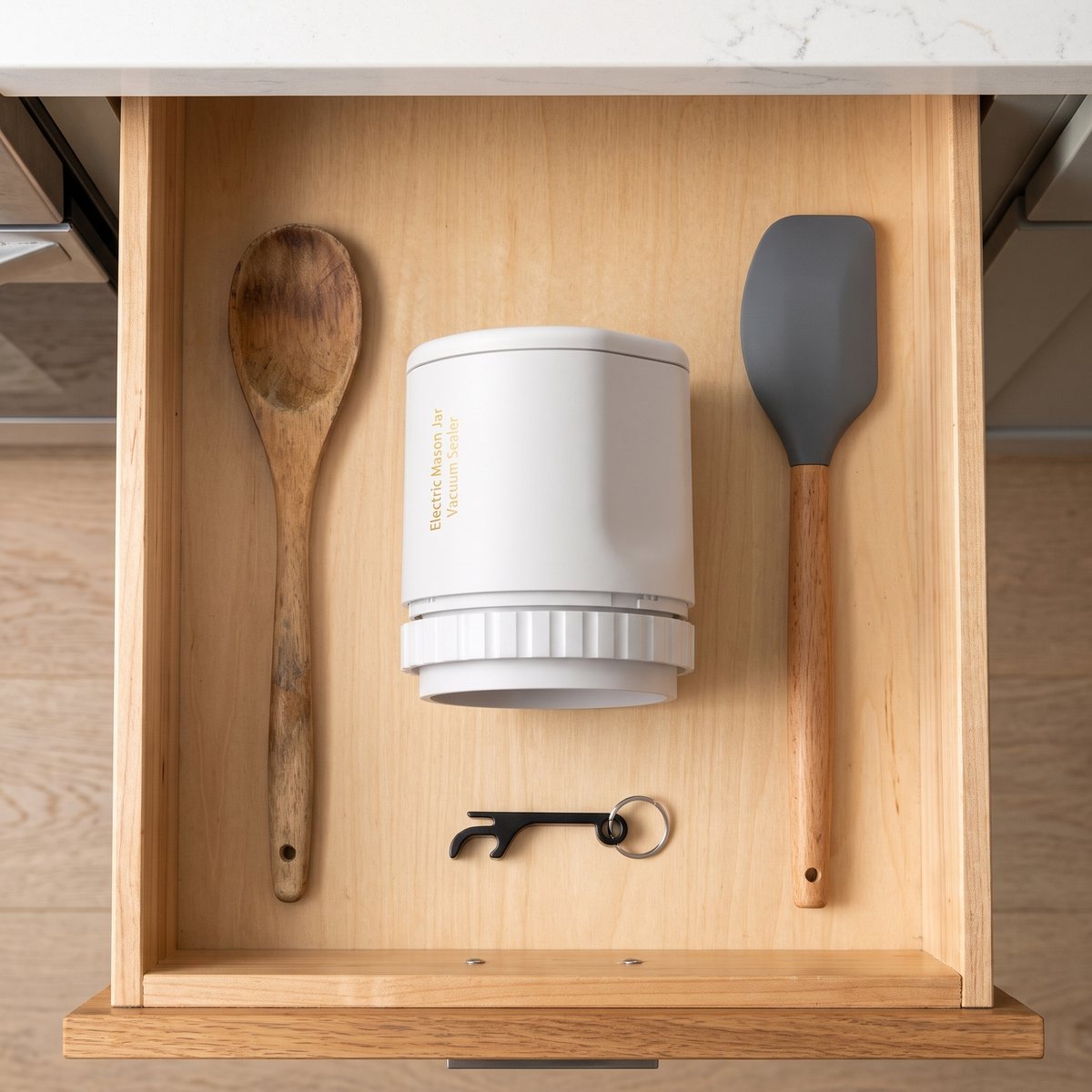 The sealer lying in a kitchen drawer between a wooden spoon and a spatula