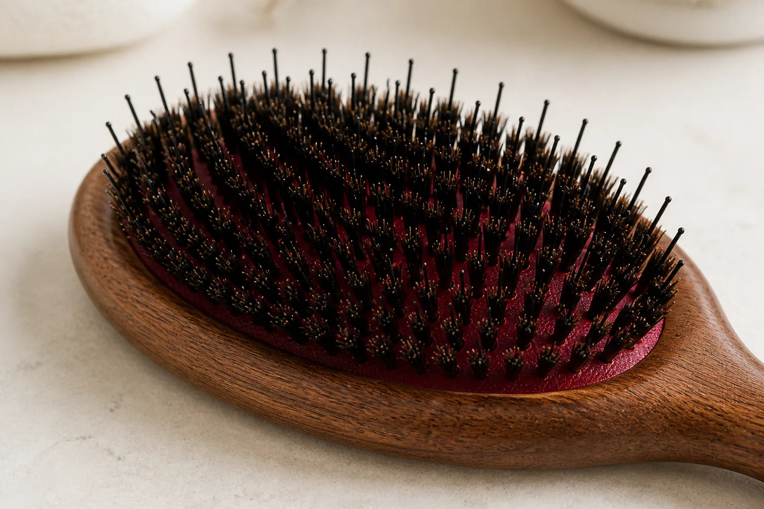 Close view of short dark boar bristles, longer rounded nylon pins, and the burgundy cushioned base